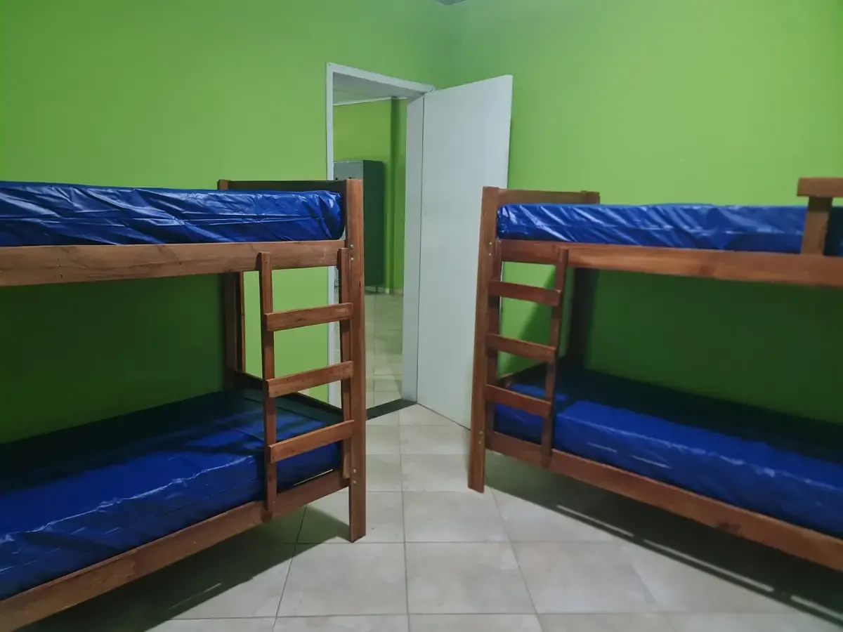 Quarto da unidade da Casa Travessia em Contagem, com paredes verdes e dois beliches de madeira